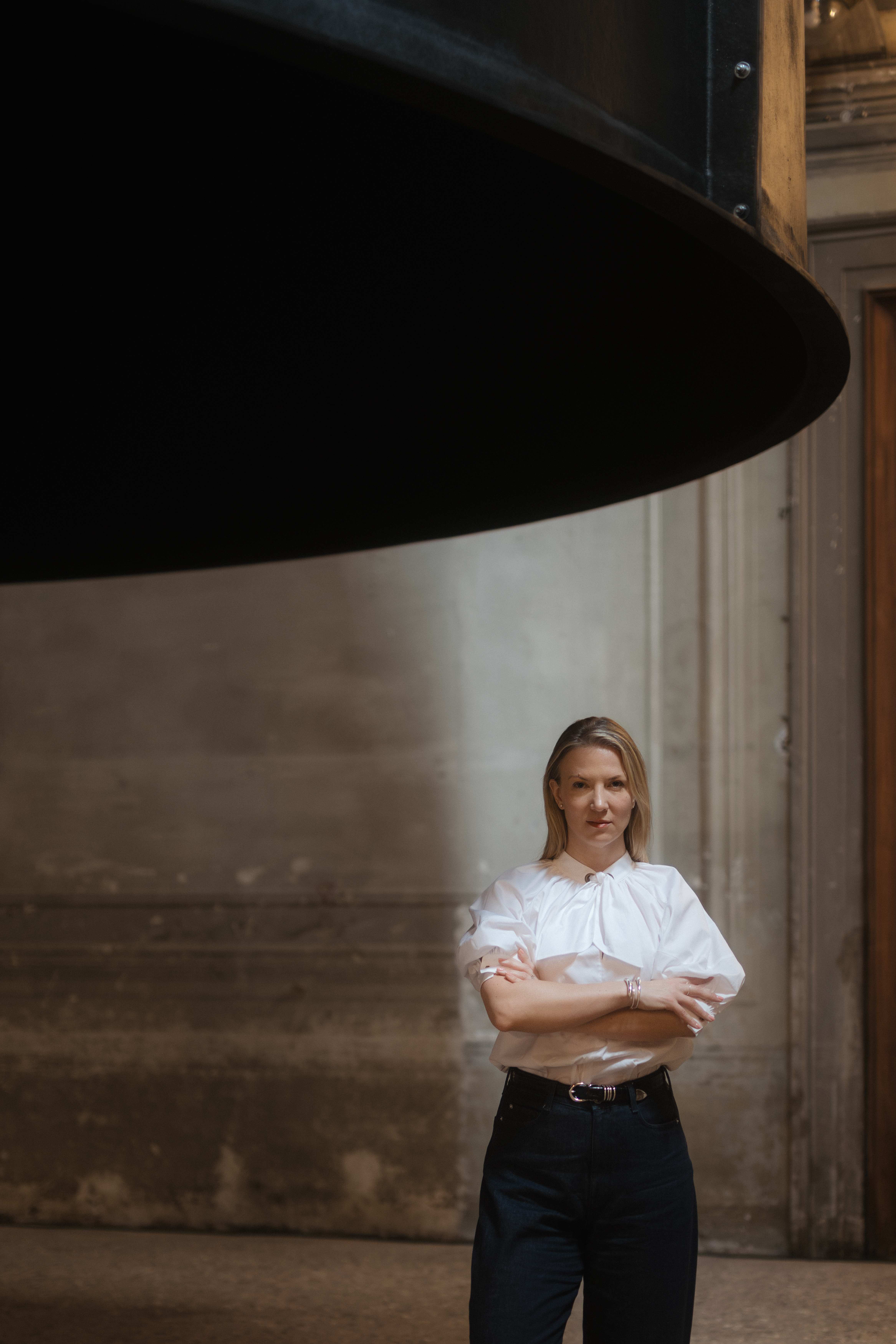 Joanna Hansen, founder of ByHansen, standing with her arms crossed in a gallery space