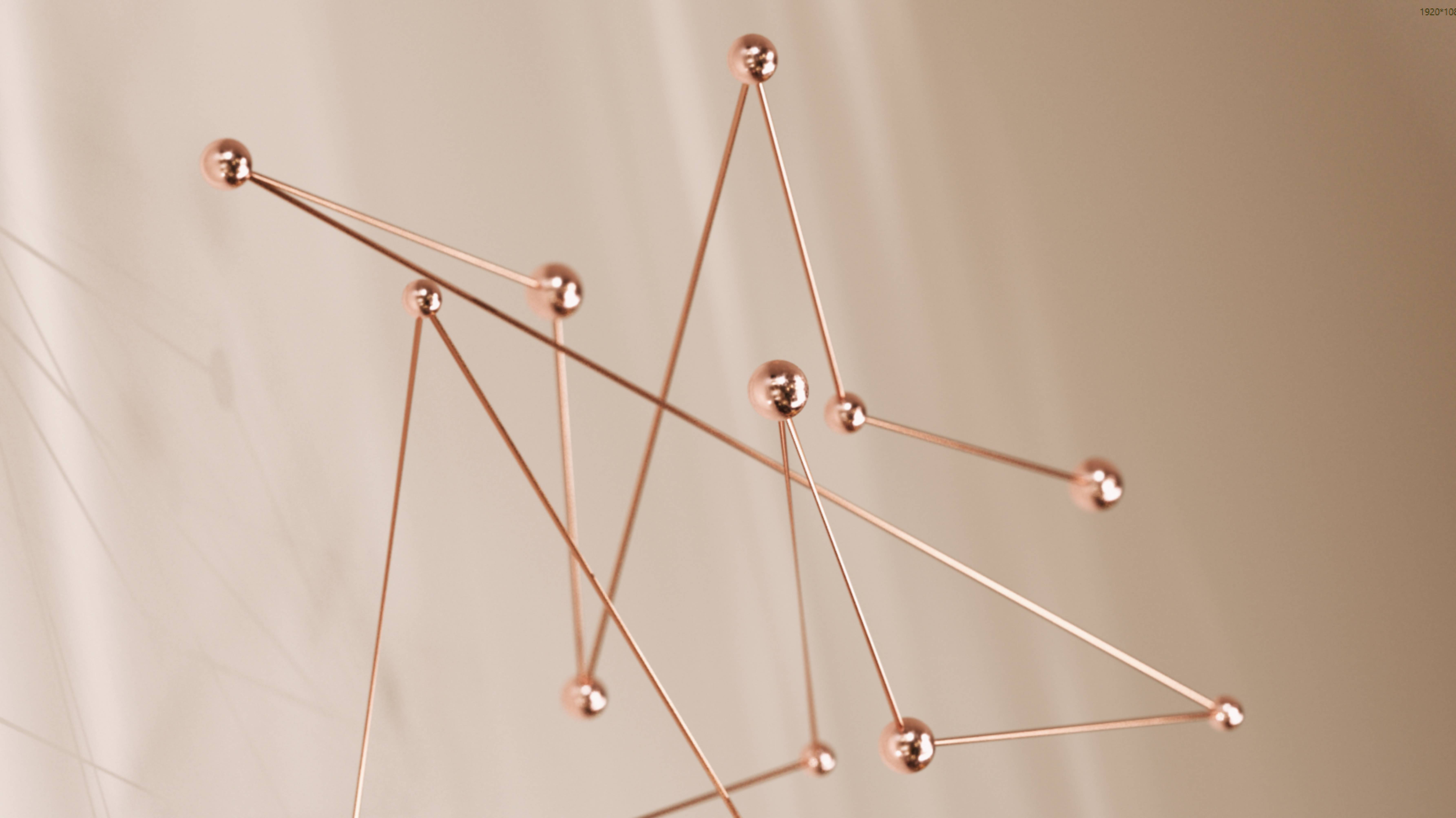 A rose-gold kinetic sculpture of slender copper rods connected by glossy spheres